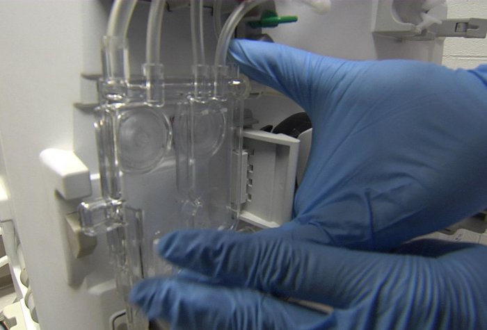Close up on technician's gloved hands handling a dialysis machine