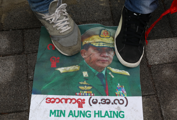 Protesters in Myanmar stand on a picture of General Min Aung Hlaing