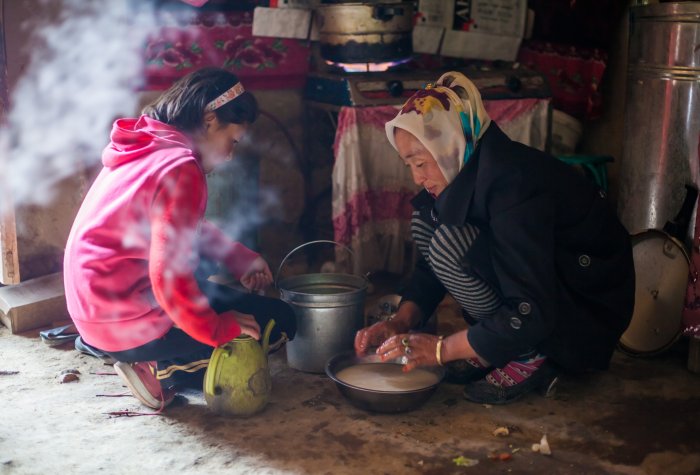 A mother and child preparing food inside a yurt in rural China.