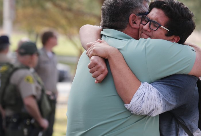 A boy hugs his father after a school shooting in Santa Clarita, CA.