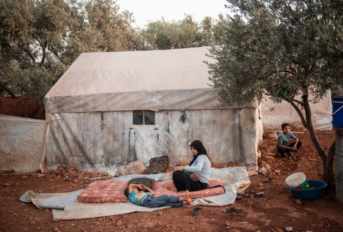 Syrian Refugees sitting in front of tent