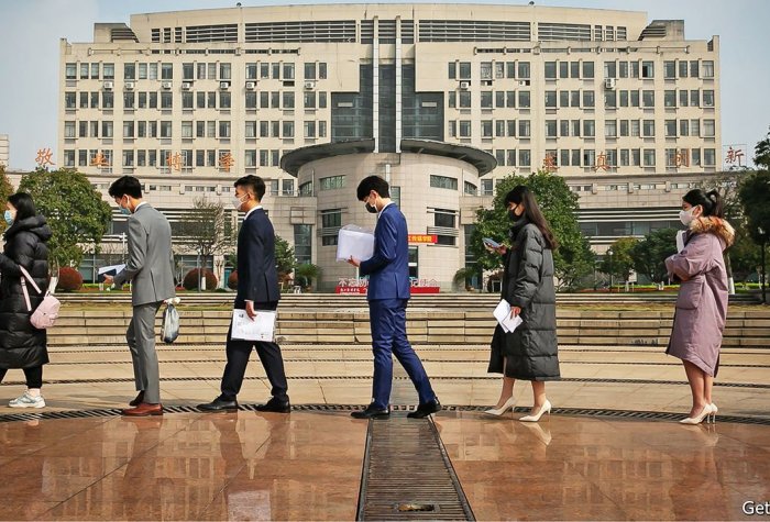 Young Chinese students stand in line in front of a large building in China.