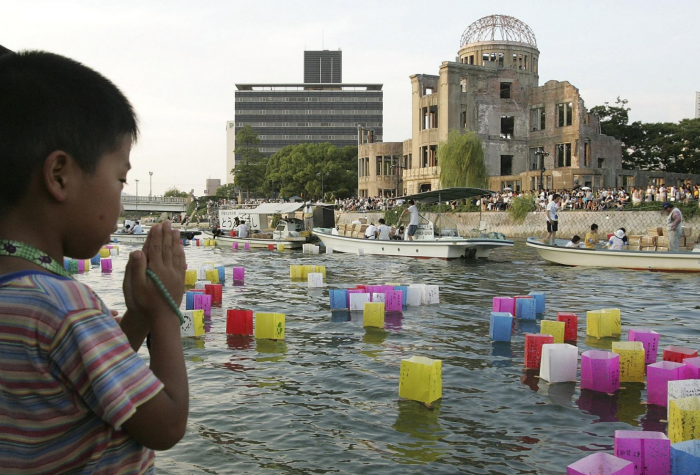 A young boy prays after releasing a floating lantern onto the Motoyasu River in front of the Atomic Bomb Dome in Hiroshima, Japan.