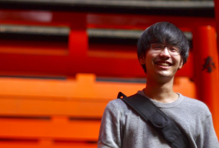 a male student standing in front of red building