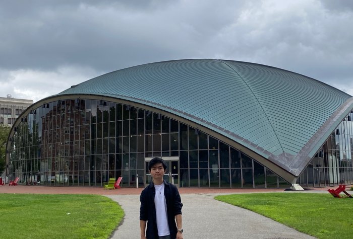 a student standing in front of a modern-looking building