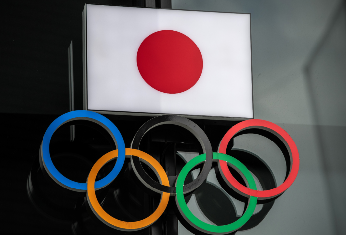 The flag of Japan is displayed over the Olympic rings.