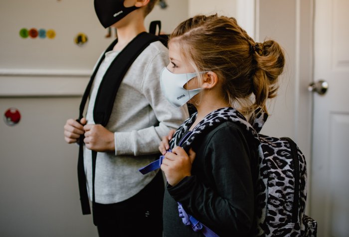 A young girl heads back to school with a mask.