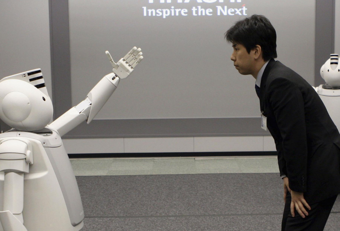 A man with interacts with 'Emiew,' a humanoid robot.