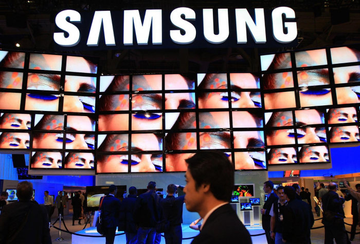 Show attendees watch a flat-screen television display at the Samsung booth during a convention