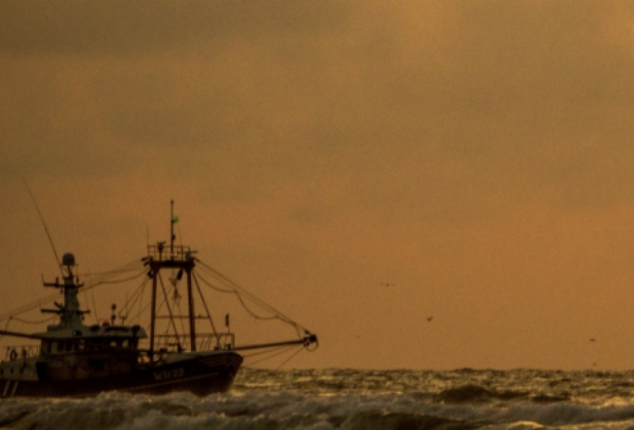 A fishing boat at sea under a hazy sky