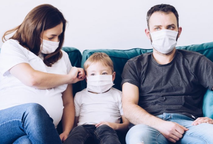 Family sits on couch with masks