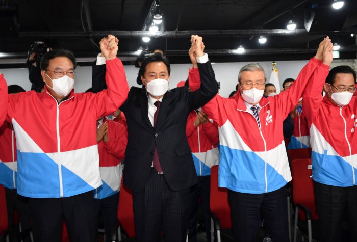 South Korean men standing up, wearing face masks, holding hands and cheering