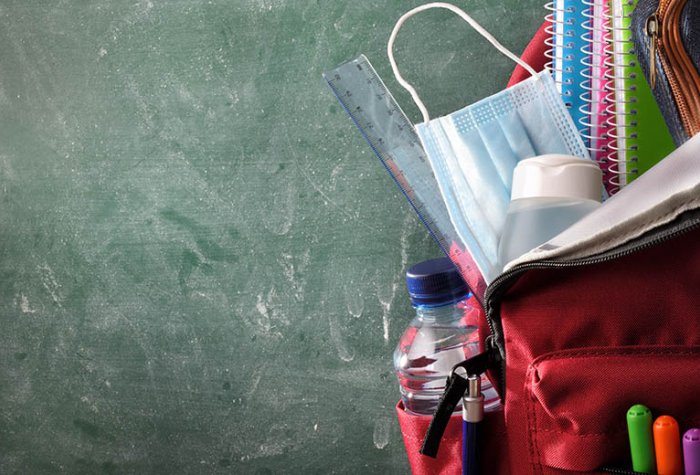 A surgical mask is tucked into a pupil's school backpack.