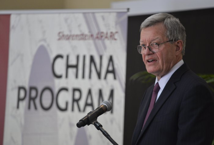 A man speaking at a podium; in the background, a banner reads "Shorenstein APARC China Program"