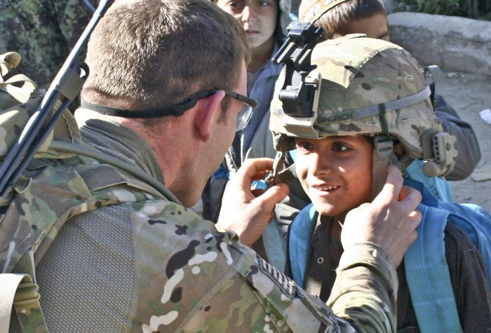 U.S. Army 2nd Lt. Taylor Gingrich draws a smile from a small Afghan boy as Gingrich lets the boy wear his helmet at Quala e’ Najil School in Najil, Laghman Province, Afghanistan, on Jan. 3, 2011. ethics sagan
