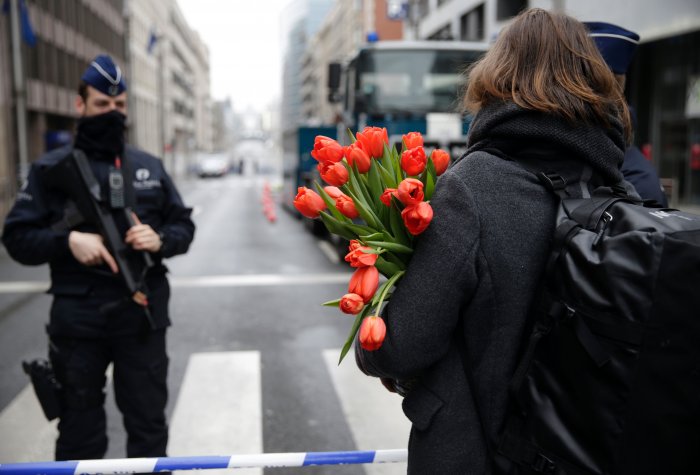A woman arrives with flowers at a cordoned-off area near Maelbeek subway station in Brussels on March 23, 2016, a day after bomb attacks in the Belgian capital killed about 35 people and left more than 200 people wounded. A woman arrives with flowers at a cordoned-off area near Maelbeek subway station in Brussels on March 23, 2016, a day after bomb attacks in the Belgian capital killed about 35 people and left more than 200 people wounded.