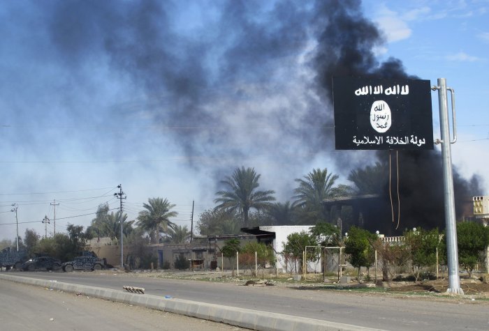 Smoke rises behind the Islamic State flag after a battle with Iraqi security forces and Shiite militia in the city of Saadiya in November, 2014. isis flag reuters rtr4fed5