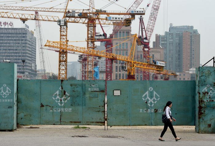 A woman walks past a construction site in Beijing, China, Sept. 2014. (Photo credit: GREG BAKER/AFP/Getty Images) urbanization beijing