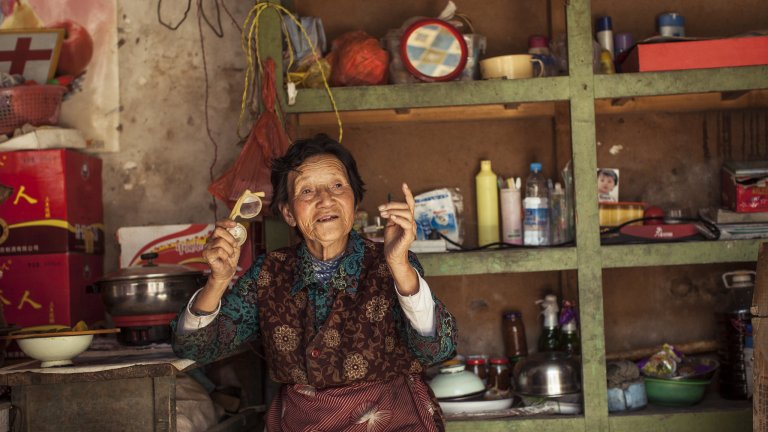 Older Tibetan woman sits in her living room in China.