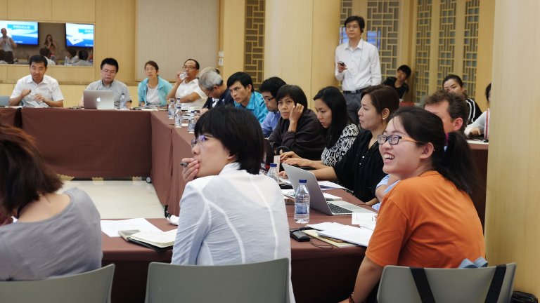 Young scholars seated around a conference room during a speaker's presentation. Young scholars seated around a conference room during a speaker's presentation.