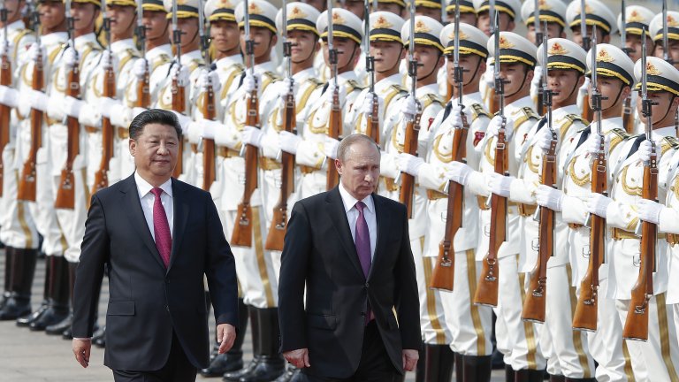 Photograph of Xi Jinping and Vladmir Putin walking in front of two lines of armed Chinese soldiers