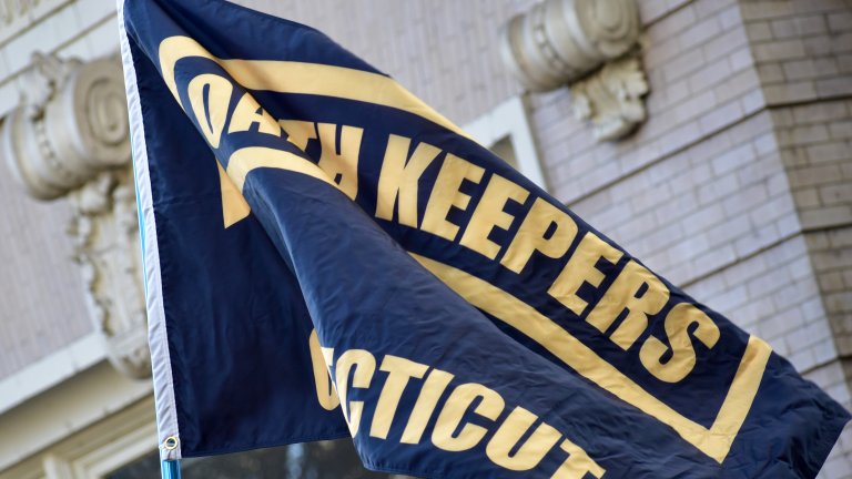 Image displays a black flag with Oath Keepers written on it in yellow text