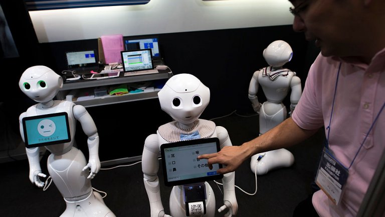 An attendant uses a tablet computer on a SoftBank Group Corp.'s Pepper humanoid robot at the Robodex Trade Show, Tokyo, Japan, 2017